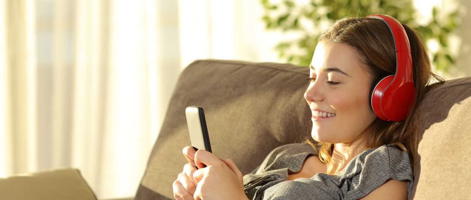 A teen and technology listening to headphones while on her phone