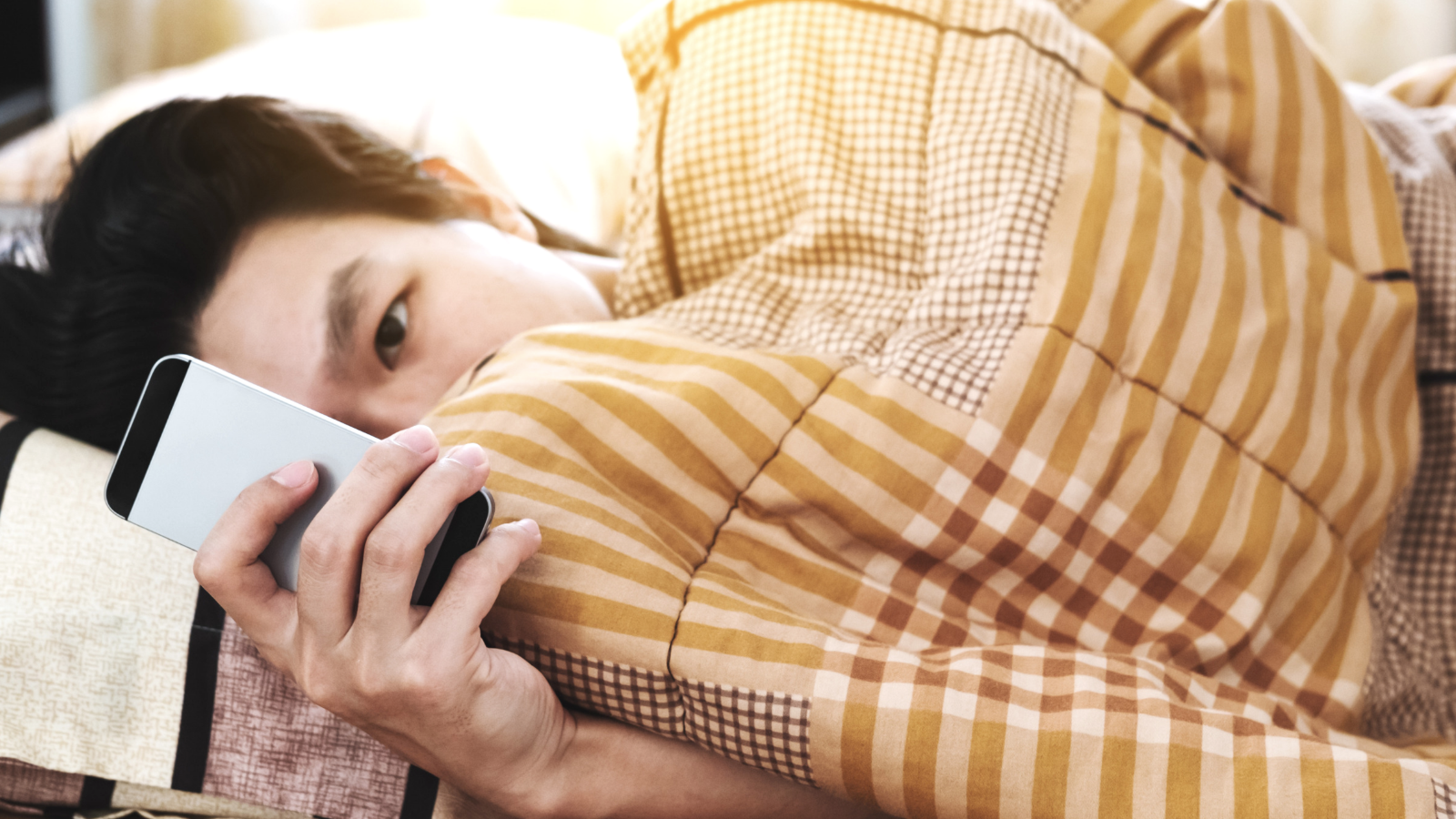 Teen in bed looking at cell phone