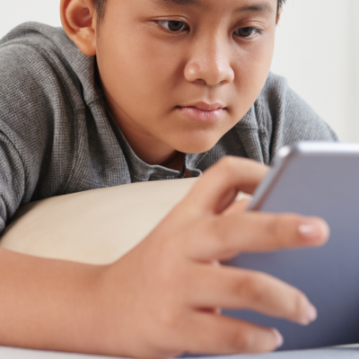 Teen reading on digital tablet lying on bed