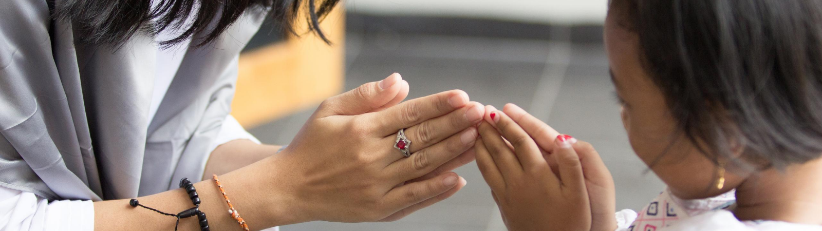 Child pressing folded hands against parents hands in an act of apology