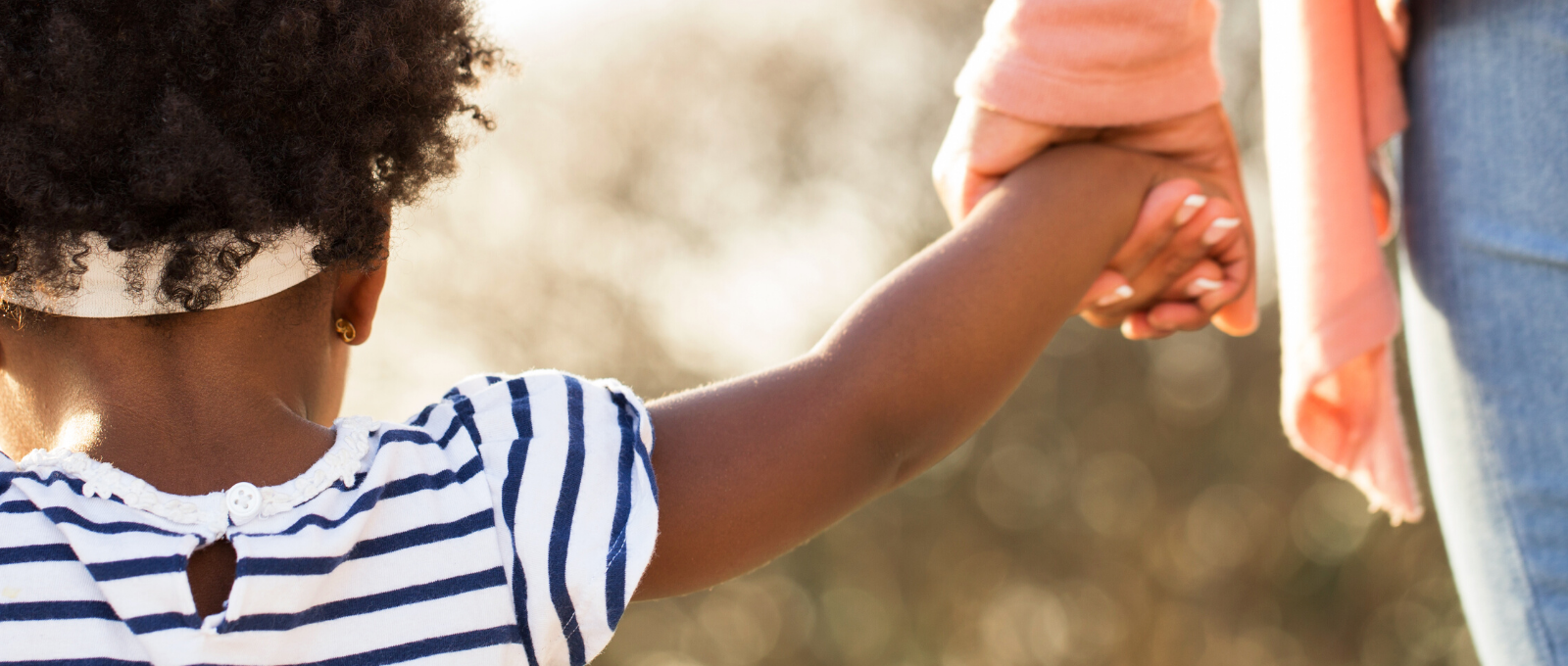 Small child holding hands with their parent staying connected during challenge