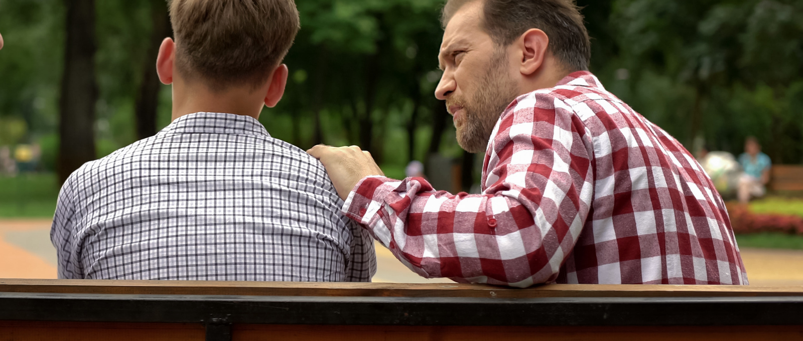 Dad putting hand on shoulder of teenage son to stay connected