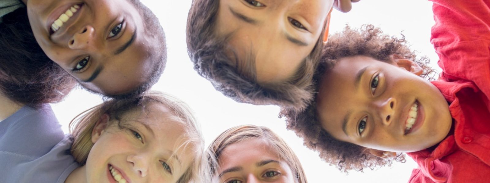 Kids and teens in a circle with their heads together
