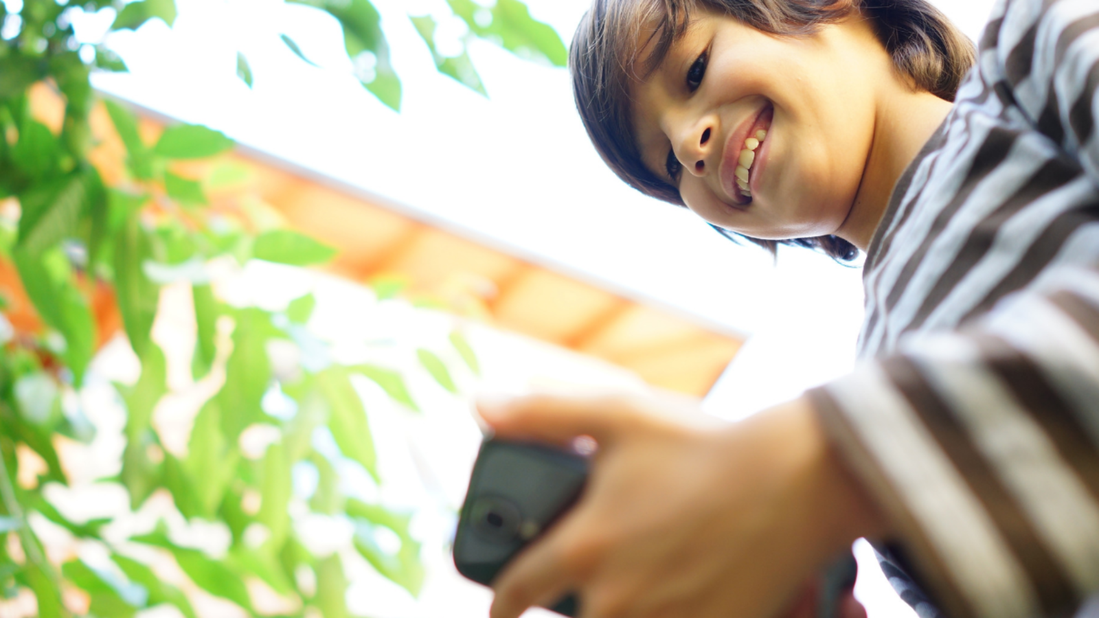 Teenager looking at his phone with a smile on his face, demonstrating good digital citizenship