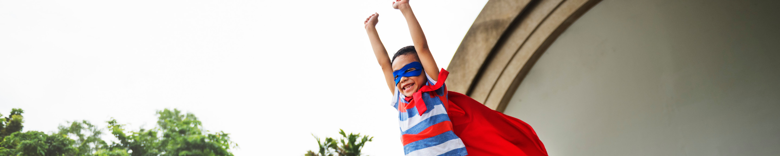 Child in superhero cape displaying courage