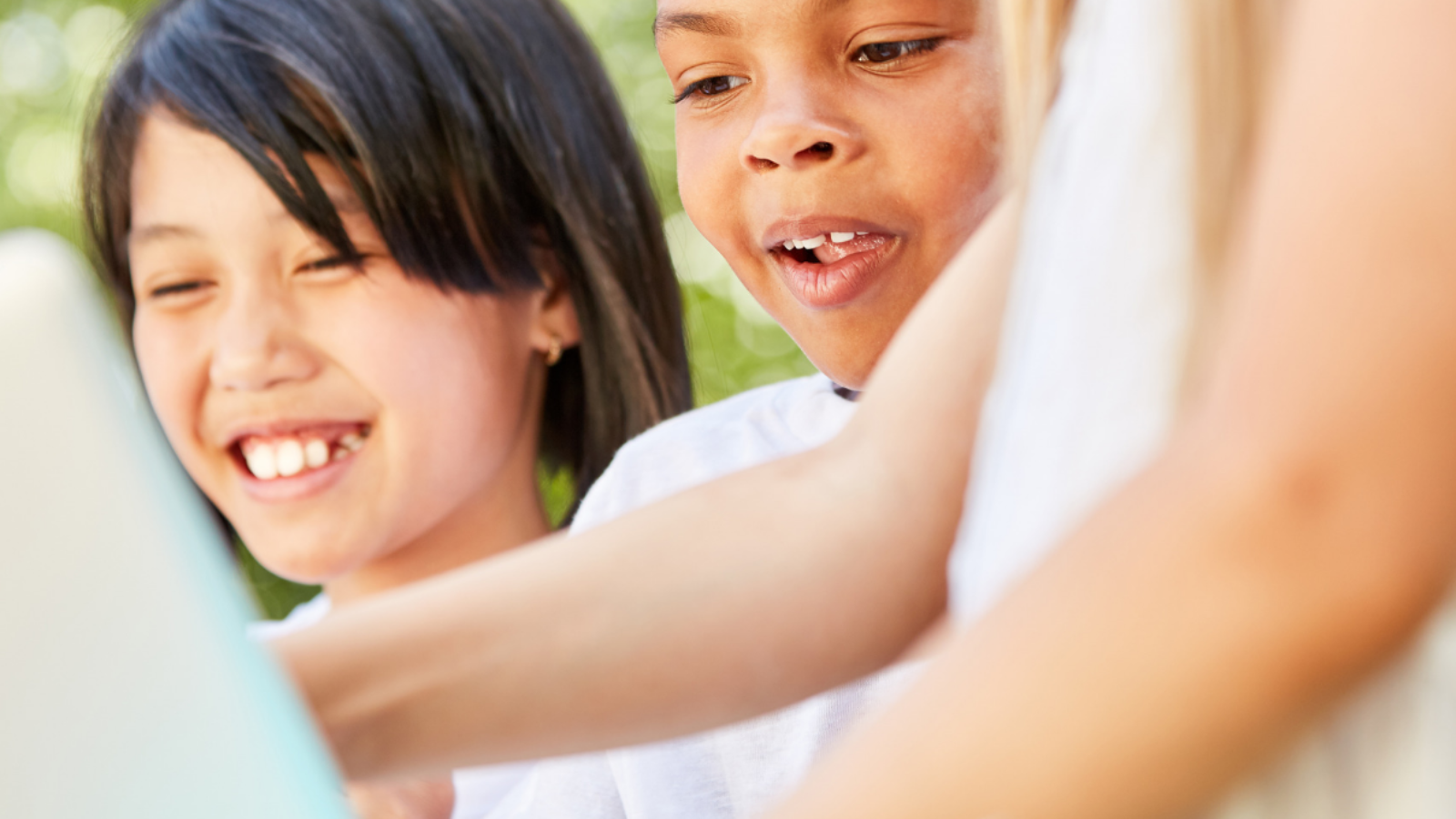 Two kids using a tablet with an adult