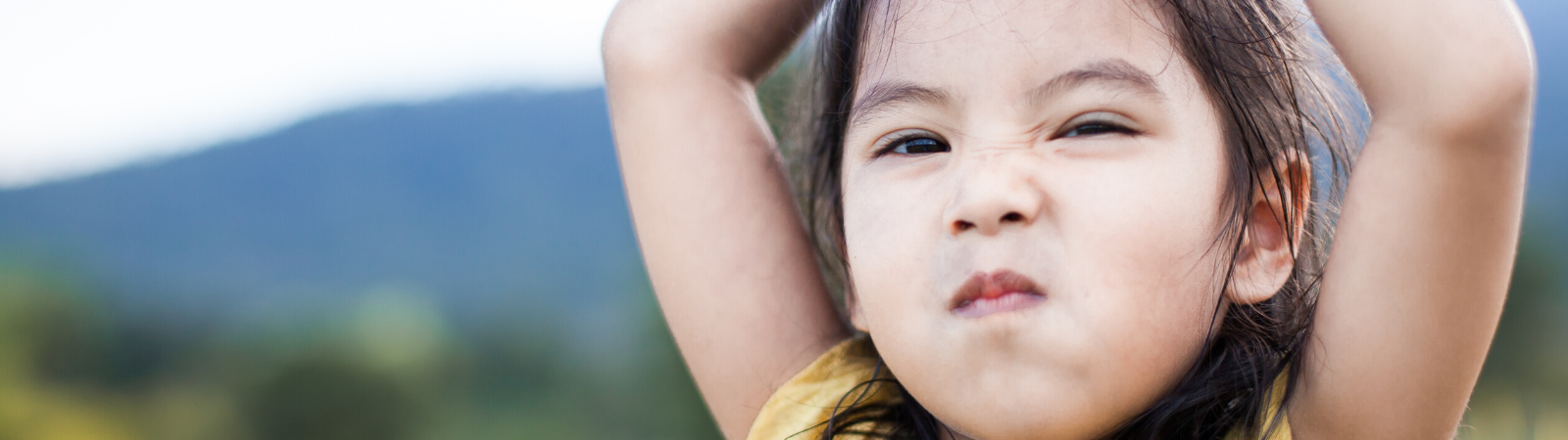 Child raising her arms in defiance feeling lots of emotions