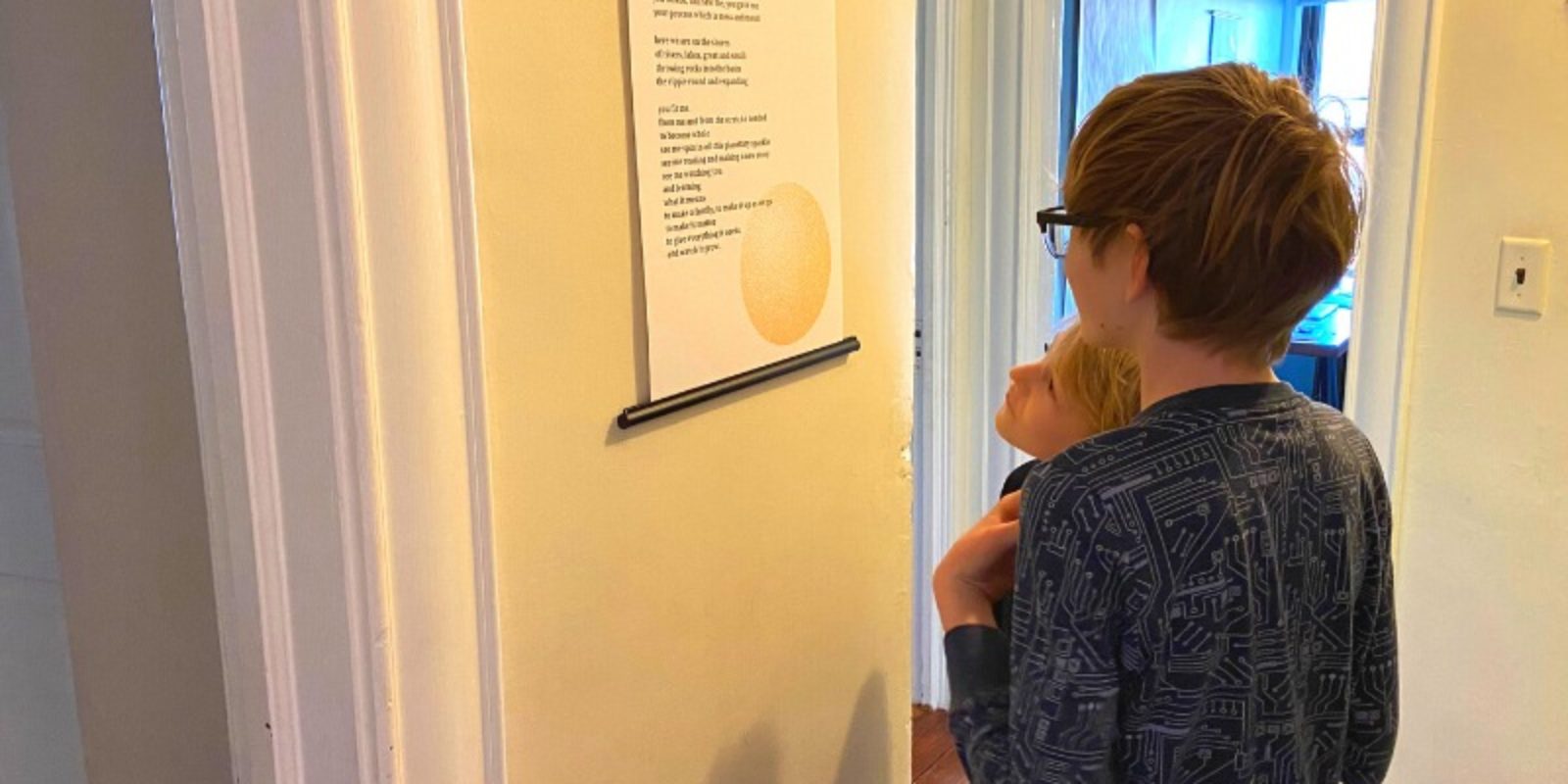 Two kids standing in the hallways reading their family poem