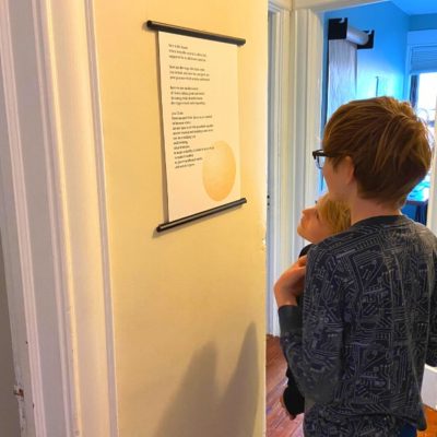 Two kids standing in the hallways reading their family poem