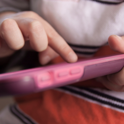 Young child scrolling through cell phone app that uses persuasive design to shape the user's behavior