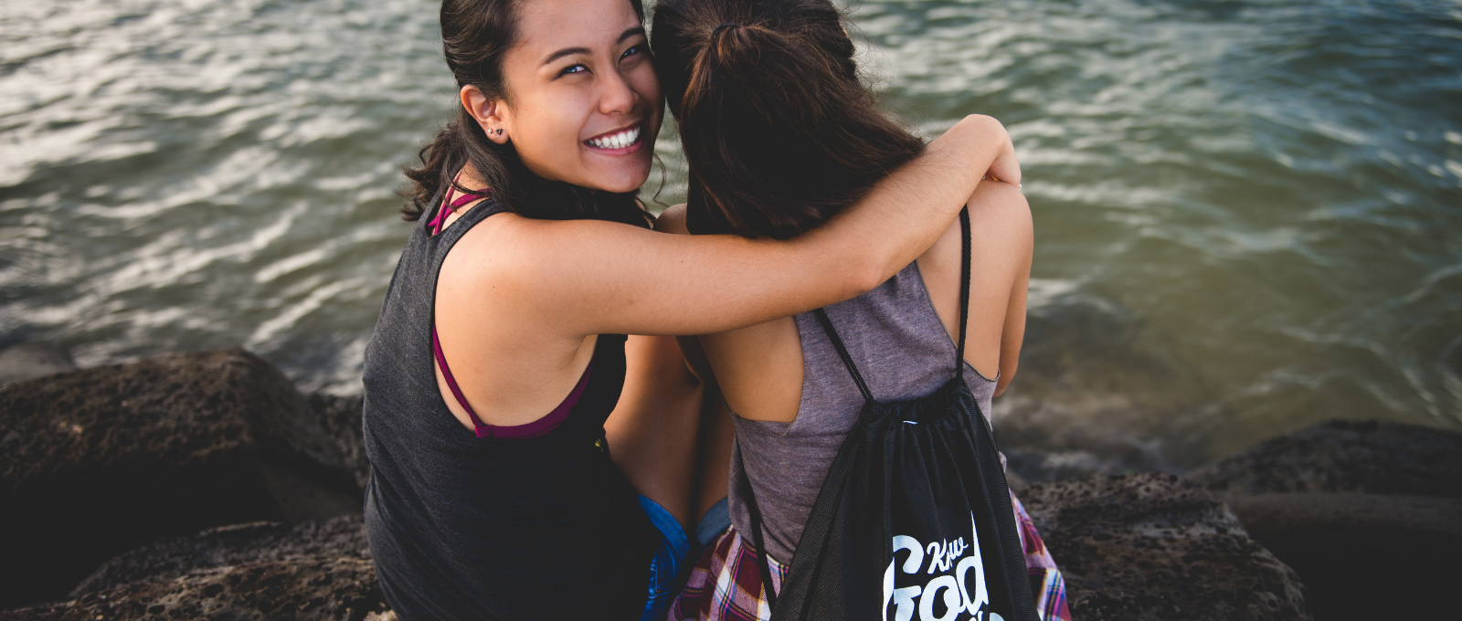 Two friends taking a break from technology in front of a lake.