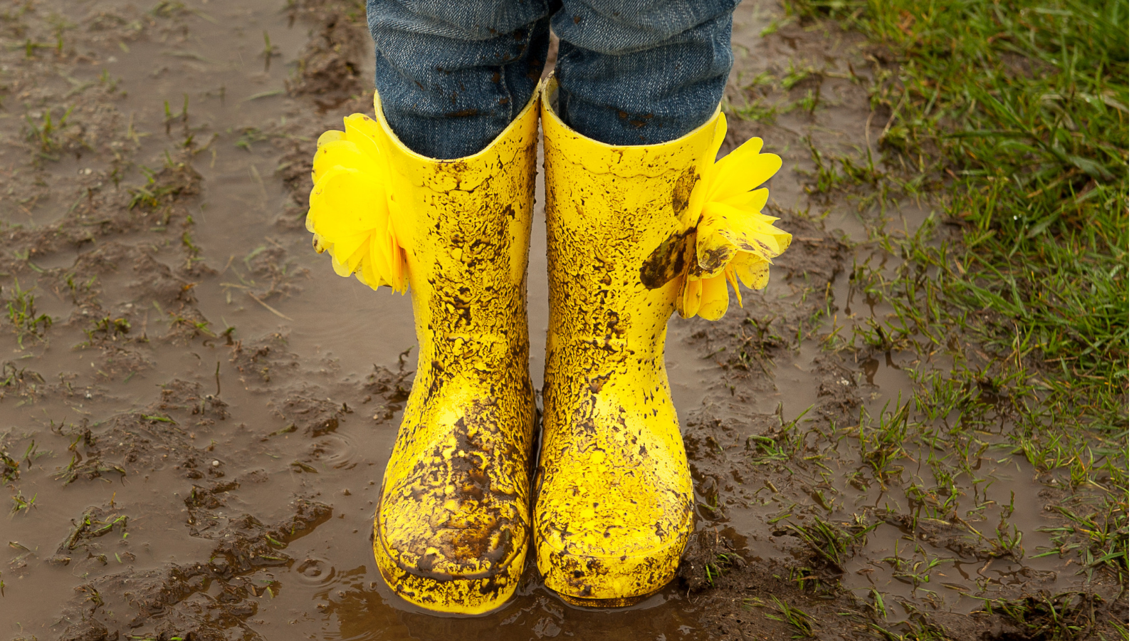 Child's bright boots in muddy puddle indicating resilience