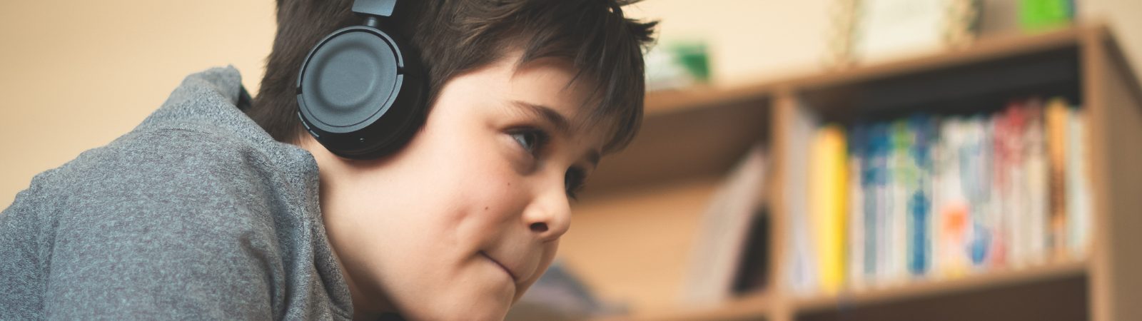 Child laying on stomach playing video games with a headset on