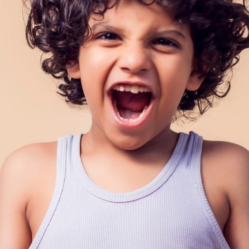 Child centered in a warm brown background expressing anger.