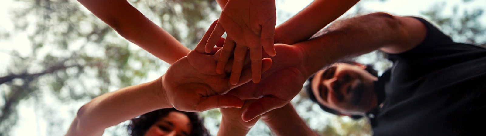 camera pointed up towards hands put together in a family team cheer