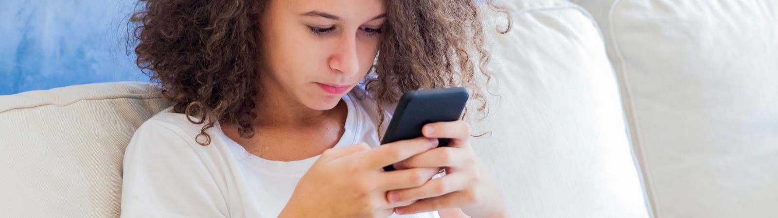 Teen girl sitting on couch looking at her iPhone