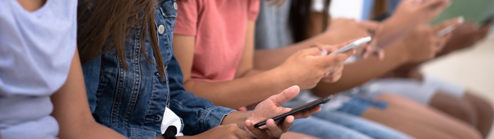 Line of teens sitting down looking at their phones