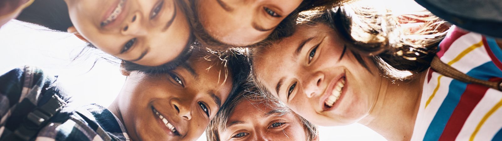 Teens looking at camera with their heads together in a circle