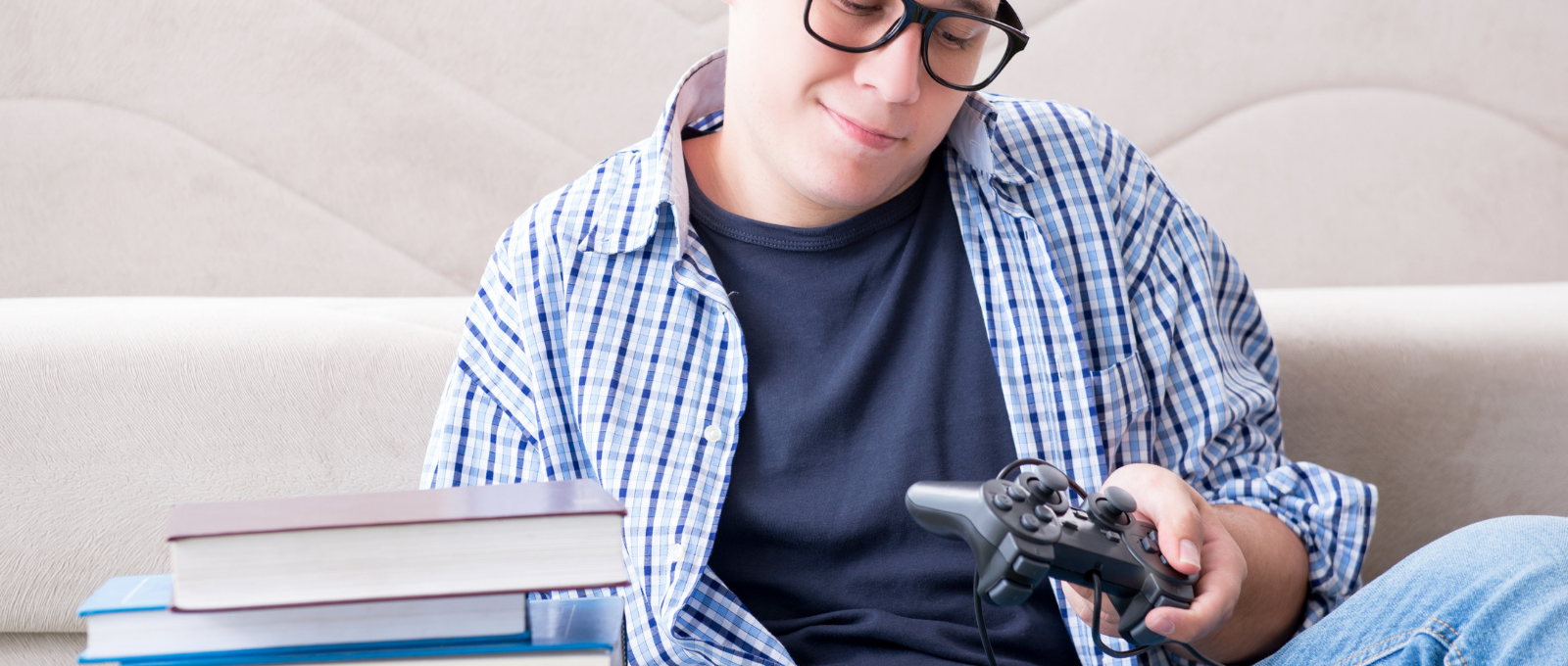 Kid sitting on couch holding video game controller and looking at books.