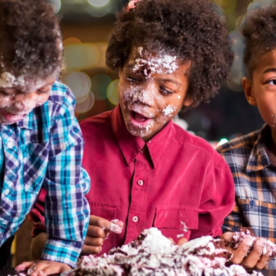 Three kids eating cake at the dining room table with crumbs all over their faces