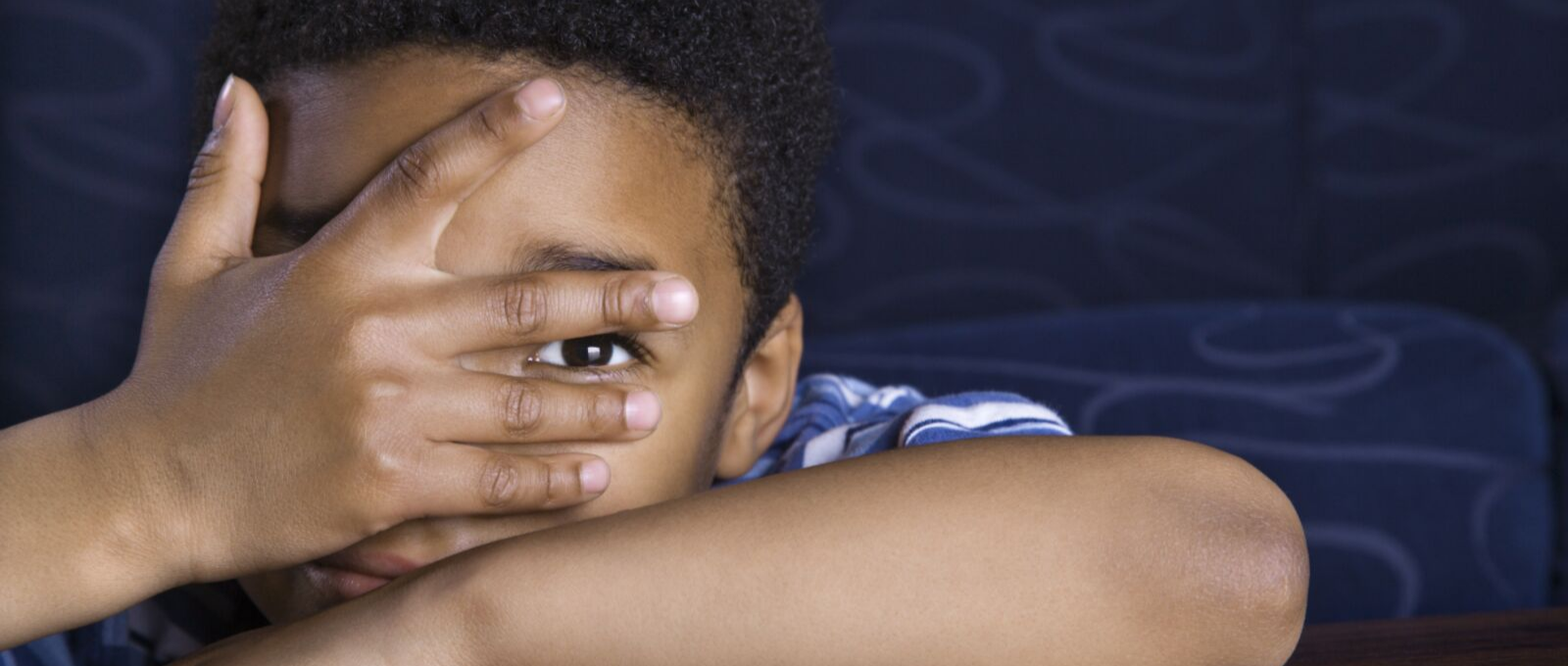 Child leaning on arms and looking through hands 