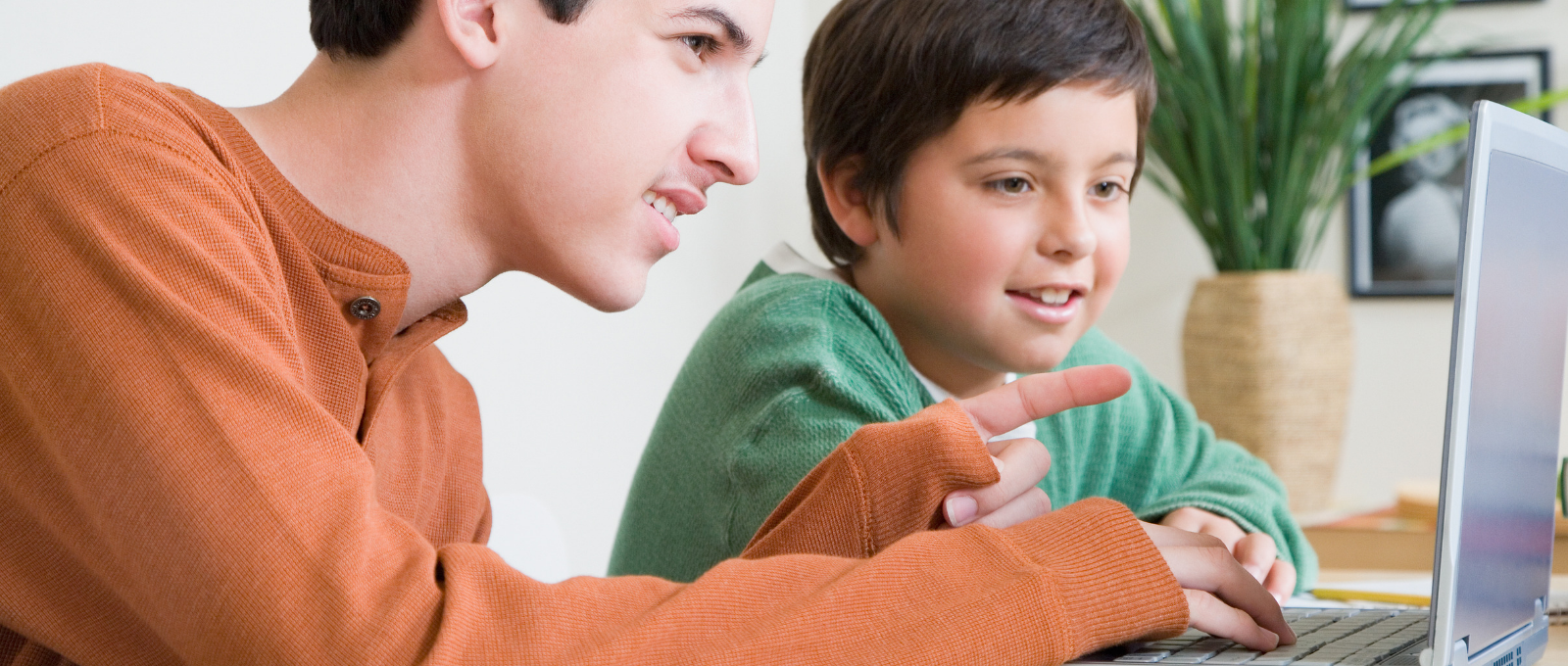 Older brother showing younger brother something fun on his laptop