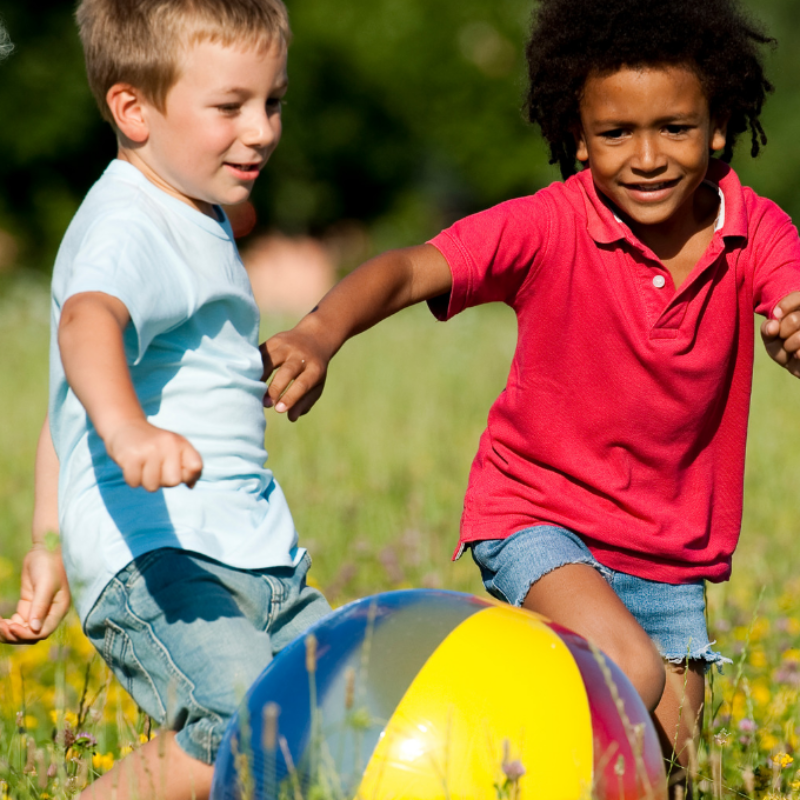 Three children engaged in free play in a field