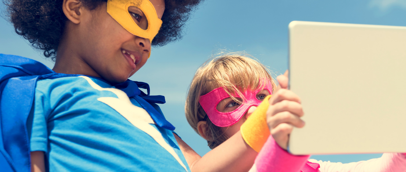 Little kids dressed like superheroes playing with tablet